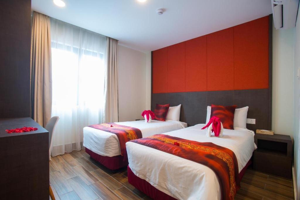 巴生的住宿－D'Spark Hotel Bayu，红色墙壁的酒店客房内的两张床