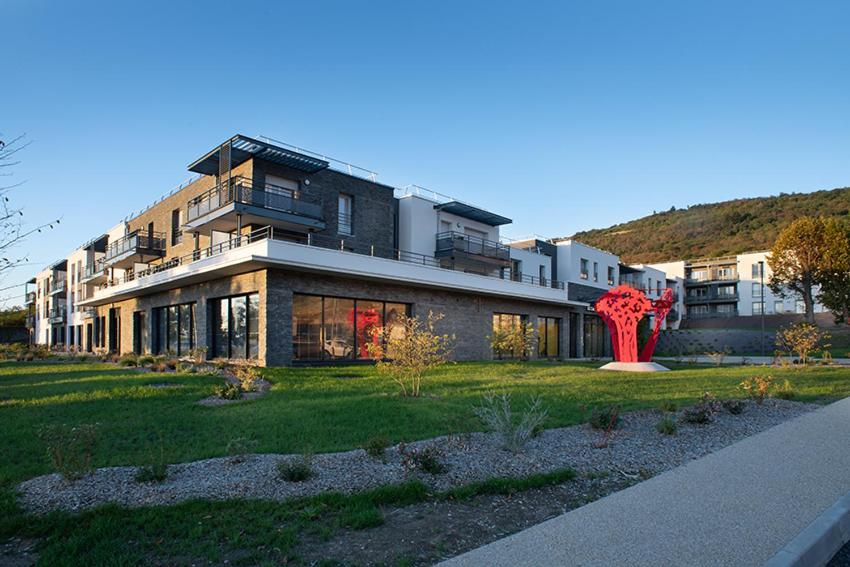 a large building with a red sculpture in front of it at Domitys - Le Castel Du Val in Pérignat-lès-Sarliève