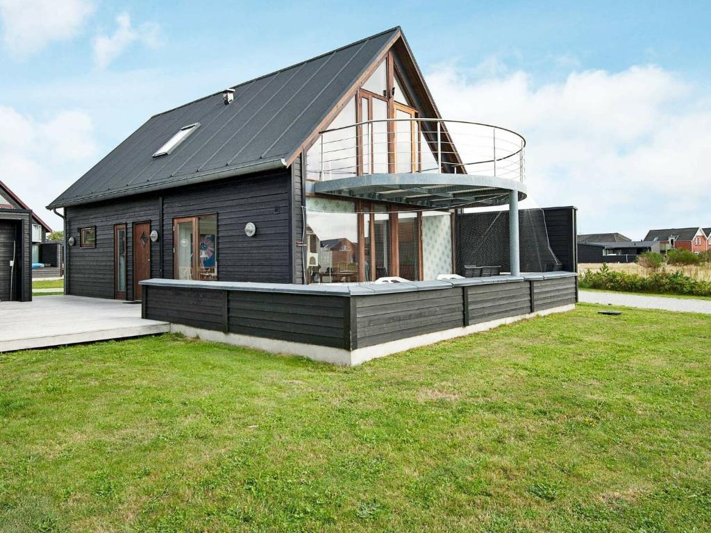 a black house with a balcony on top of a yard at 6 person holiday home in R m in Rømø Kirkeby