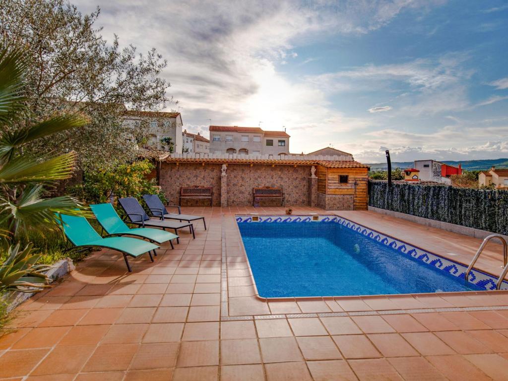 un patio trasero con piscina y sillas y una casa en Belvilla by OYO Casa Las Palmeras, en El Vendrell