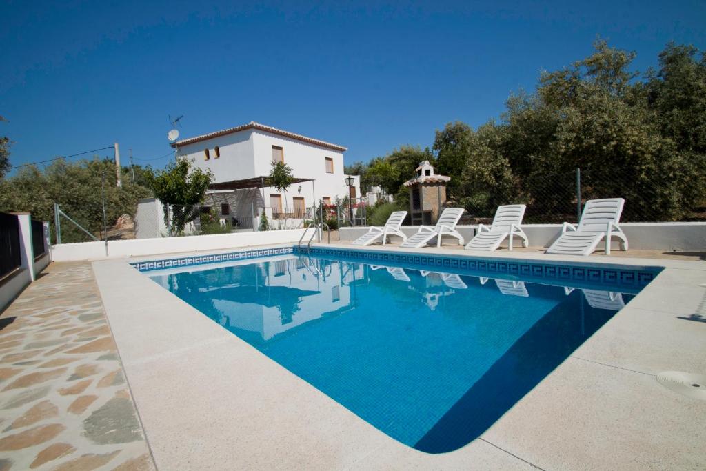 una piscina con sillas y una casa en Casa Rural La Loma en Iznájar