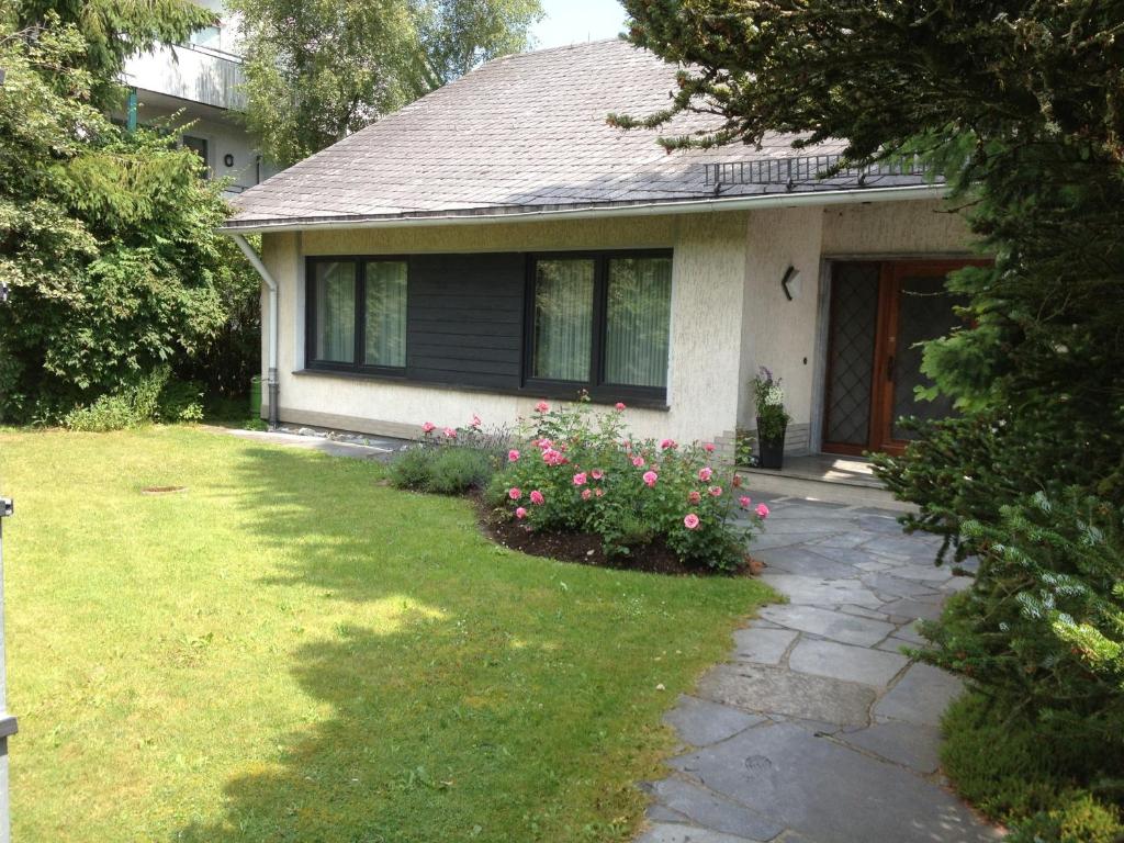 una casa con un patio con flores rosas delante de ella en Ettelsberg Appart, en Willingen