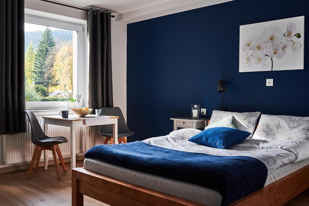 sypialnia z niebieską ścianą z łóżkiem i stołem w obiekcie Apartamenty Nad Rzeką w Polanicy Zdroju
