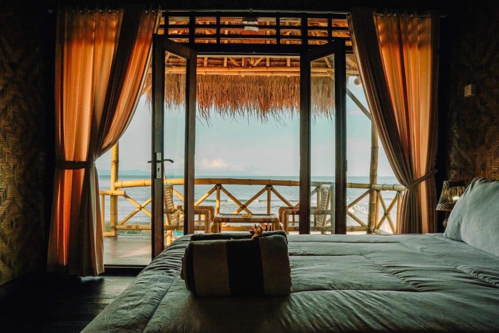 a bedroom with a bed and a large window at Pondok Bamboo Villa in Nusa Penida
