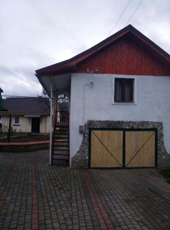a garage with a red and white building with a door at У вуйка Івана in Yaremche