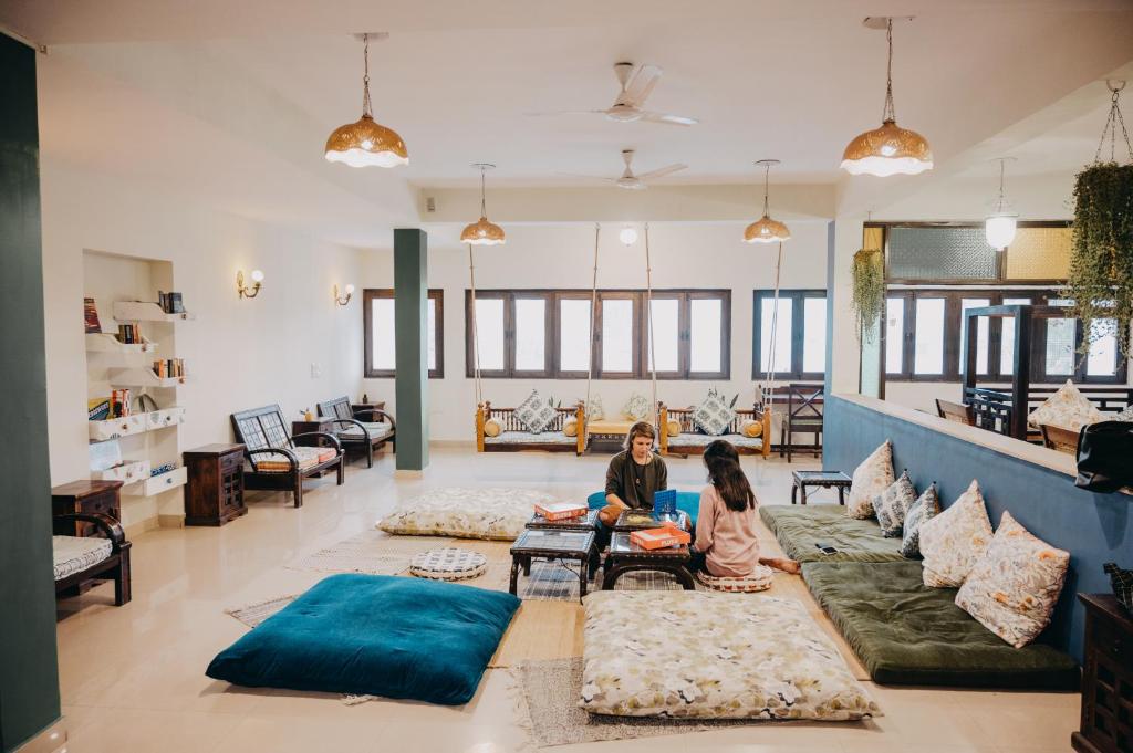 deux filles assises au sol dans un salon dans l'établissement Horn Ok Please Hostel Jaipur, à Jaipur