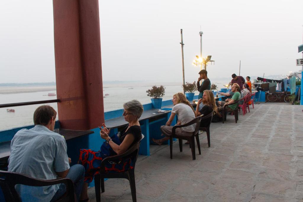 a group of people sitting at tables near the beach at Vishnu Rest House in Varanasi