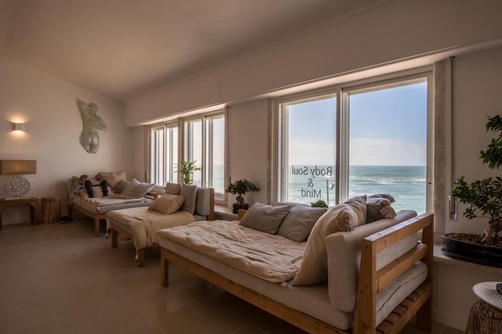 a living room filled with furniture and a large window at Sandhi House - Yoga & Wellness in Ericeira