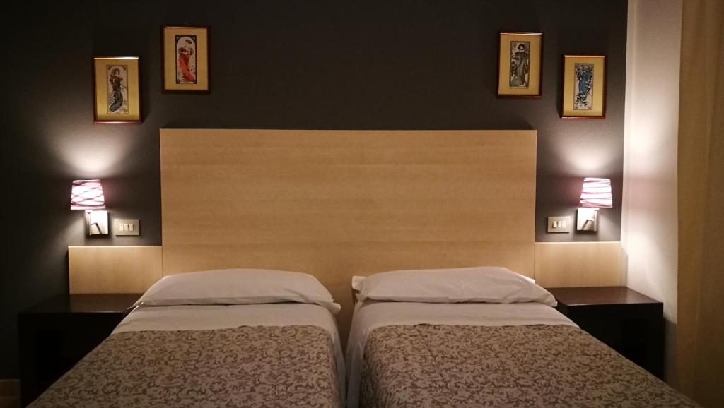 two beds in a bedroom with two lamps on the wall at Boni room and breakfast in Molinella