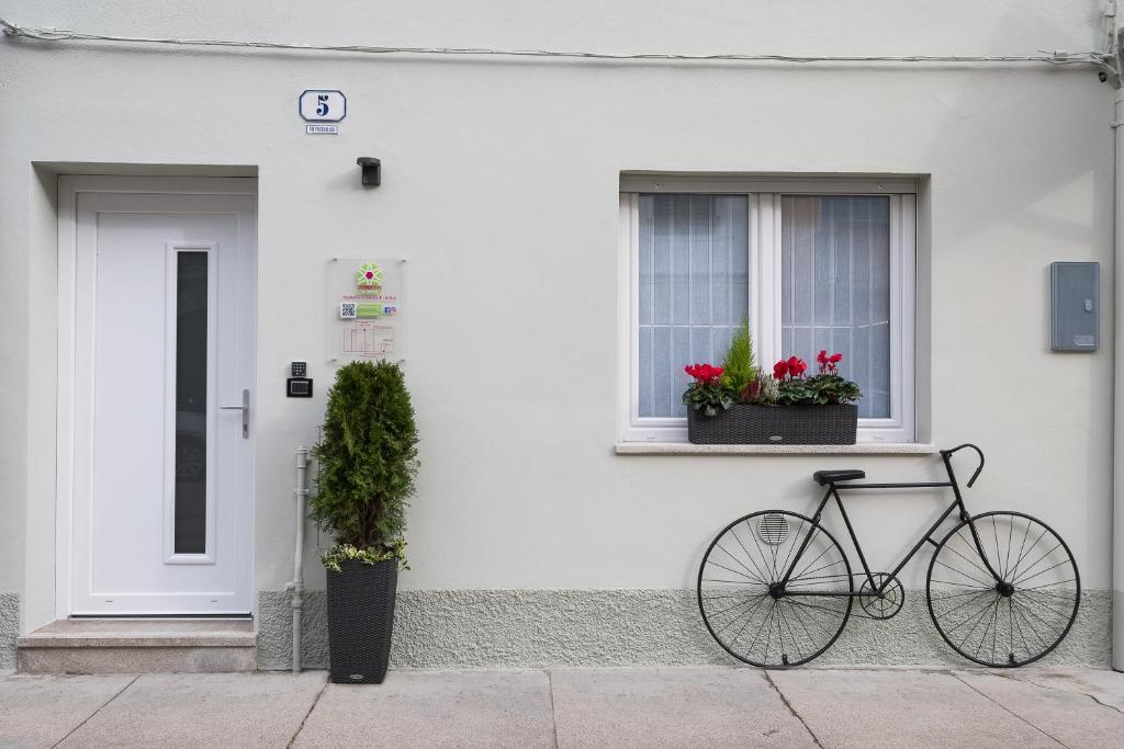 una bicicletta parcheggiata di fronte a una casa bianca con due finestre di ZONA 30 Bike Guesthouse a Palmanova