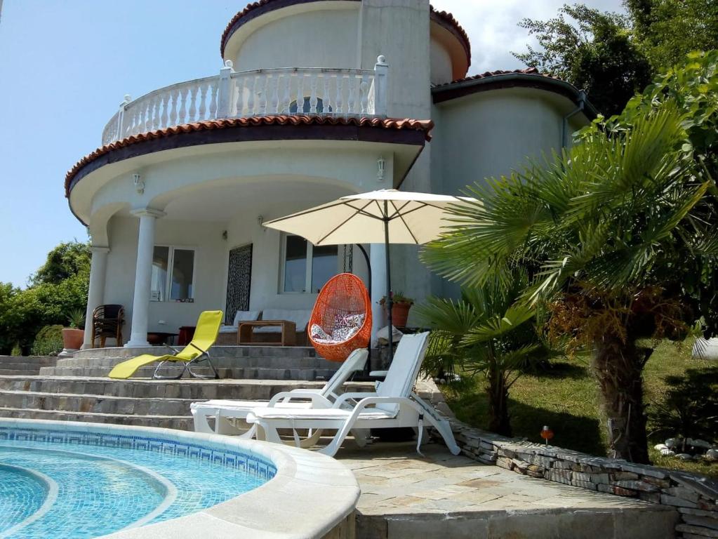 a pair of chairs and an umbrella in front of a house at Villa Sky Music in Obzor