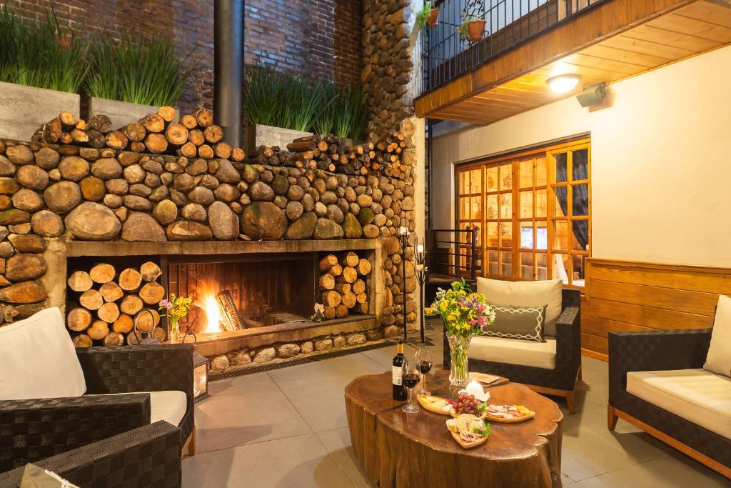 a living room with a fireplace and a table at Hotel Giardino Di Pietra in Gramado