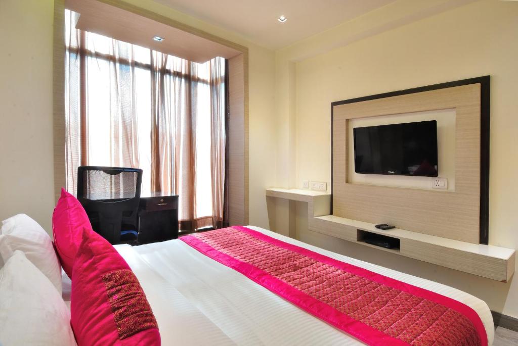um quarto com uma cama grande e uma televisão de ecrã plano em Hotel Royal Grand - Opposite Axis Bank East Patel Nagar em Nova Deli