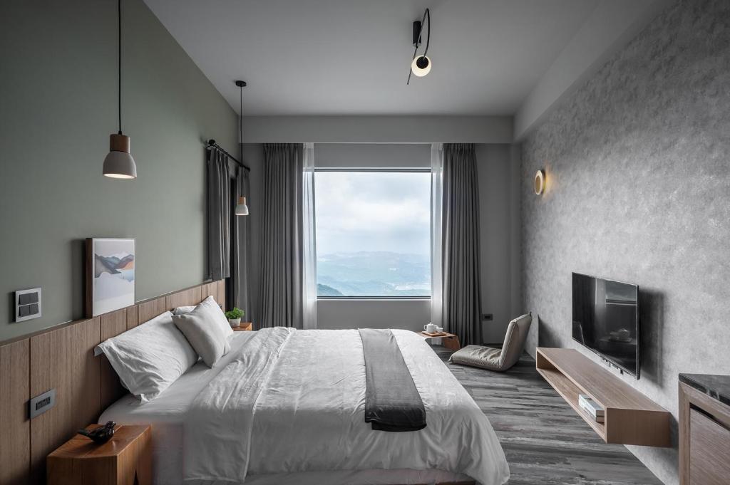 a bedroom with a large bed and a large window at Two Easy Inn in Jiufen