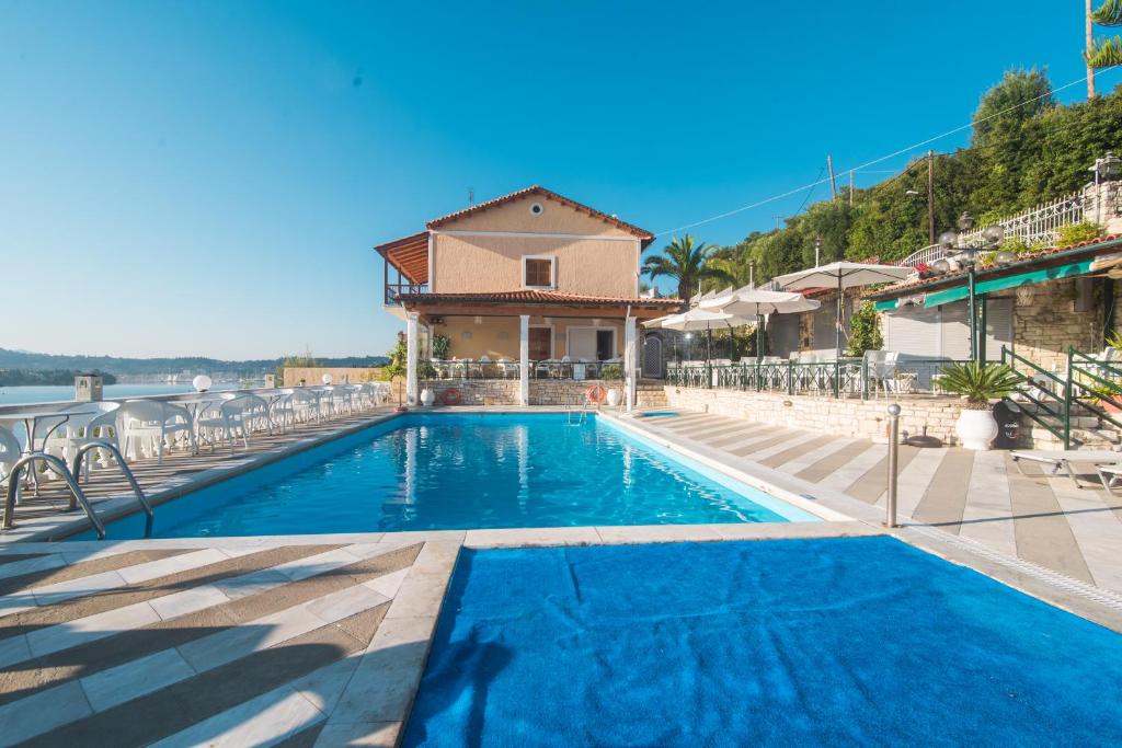 een zwembad met stoelen en een huis bij Kommeno Bay Apartments in Corfu-stad