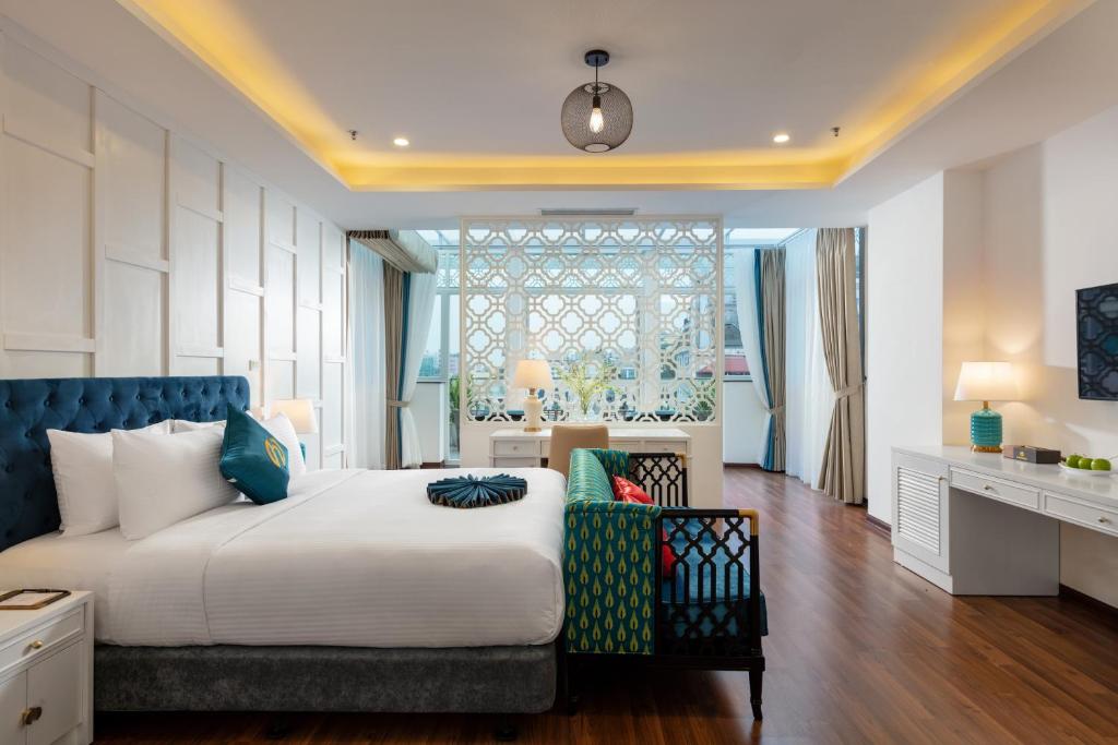 a bedroom with a large bed and a desk at Minasi HanoiOi Hotel in Hanoi
