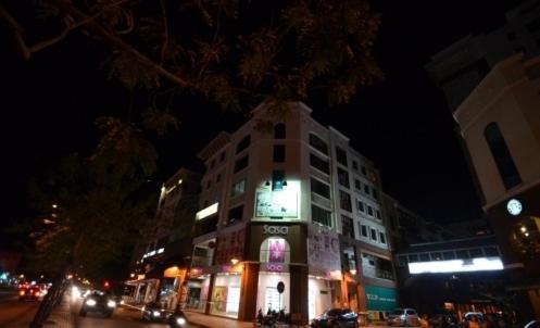 KK Waterfront Hotel في كوتا كينابالو: مبنى به لافتة مضاءة أمامه في الليل