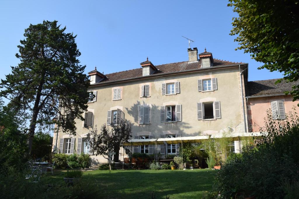 a large house with a grass yard in front of it at Chambres et table L' échappée in Bouvesse-Quirieu