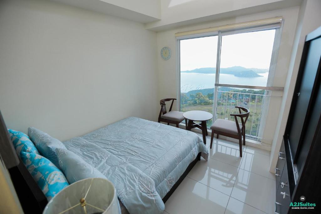 a bedroom with a bed and a table and a window at A2JSuites Bedroom Taal View Luxury Smart Home Suite Near Skyranch in Tagaytay