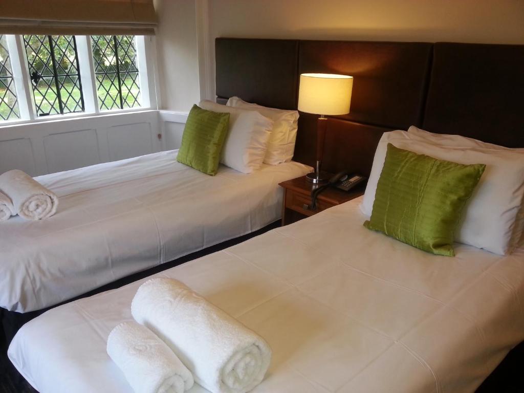 duas camas num quarto de hotel com almofadas verdes e brancas em Thornbury Lodge em Thornbury