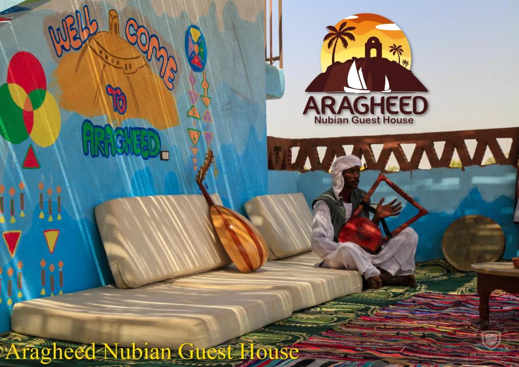 a man sitting on a couch in front of a stage at Nubian Kingdom Aragheed House in Aswan