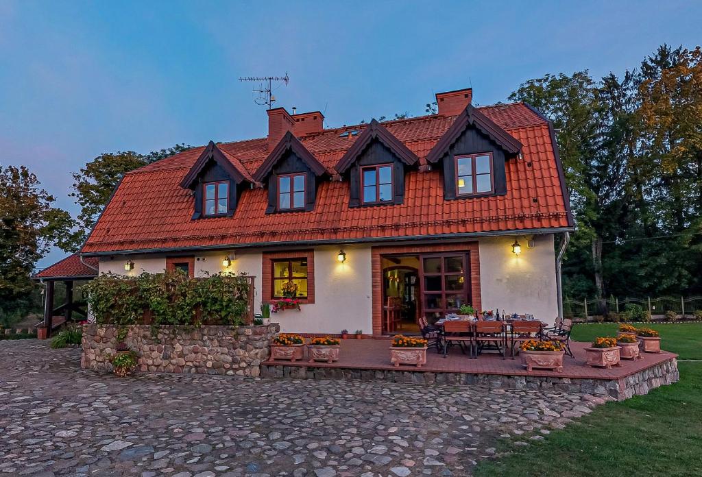 een huis met een rood dak en een patio bij Osada Ulnowo - Holliday & Party House in Grunwald