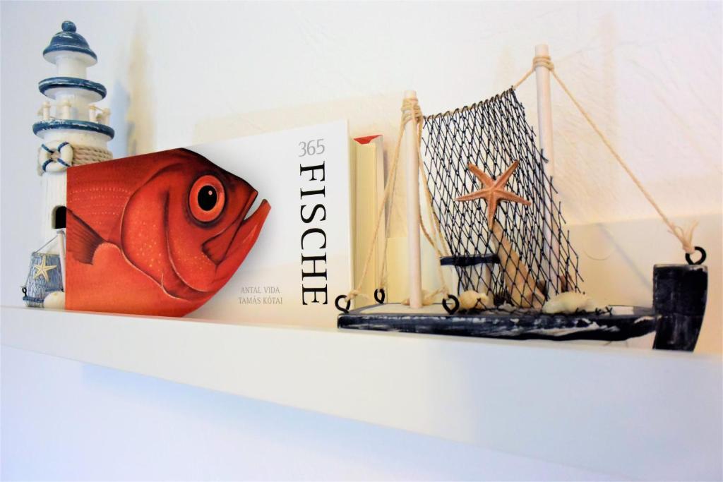 un estante con un pescado y libros. en Ferienwohnung ADMIRAL en Kühlungsborn