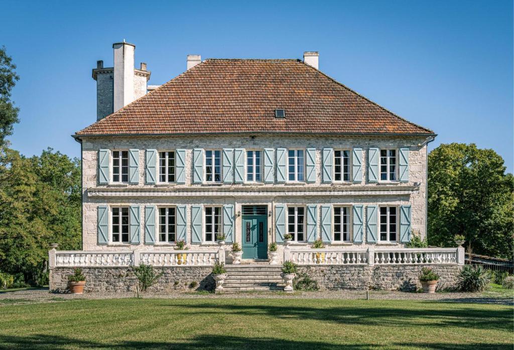 uma casa velha com uma porta verde num campo de relva em Château les Estournels em Montlauzun