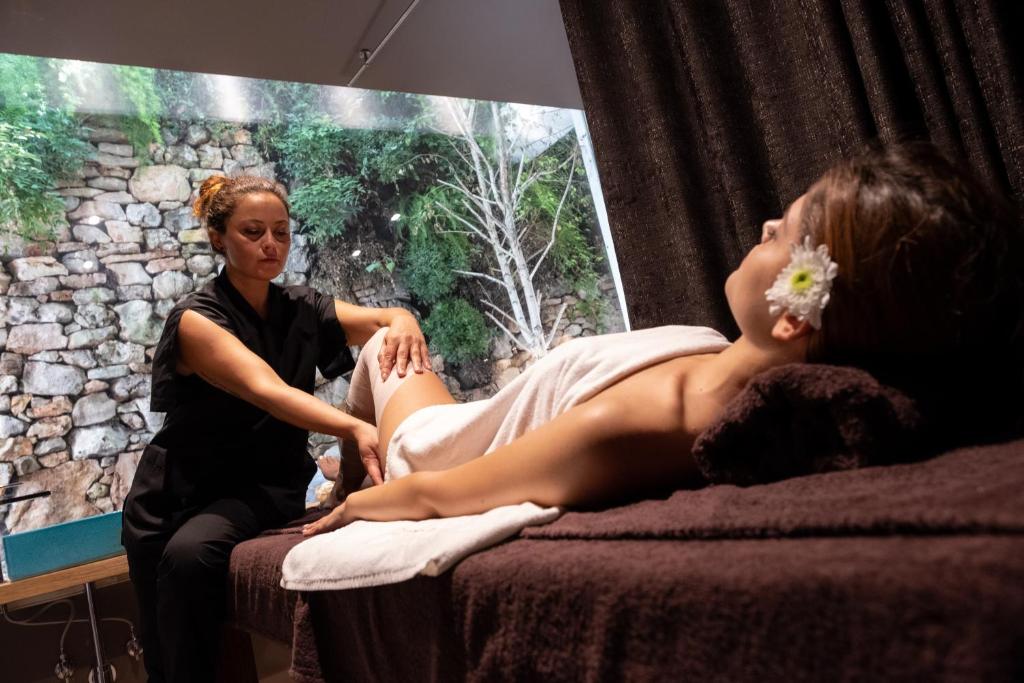 a woman sitting on a bed talking to a woman in front of a woman at Gran Paradiso Hotel Spa in San Giovanni Rotondo