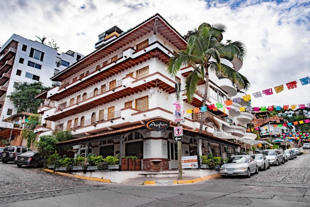 a building with a palm tree in front of a street at Olas Altas Suites Departamentos in Puerto Vallarta