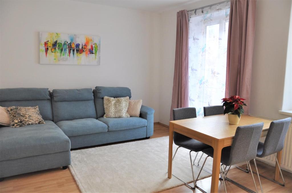 2 Schlafzimmer Apartment في لينز: غرفة معيشة مع أريكة زرقاء وطاولة