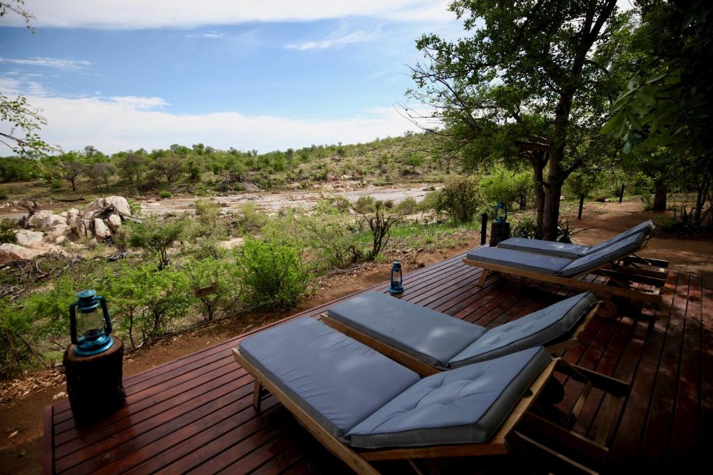 a deck with two lounge chairs and a bottle of beer at Ivory Wilderness River Rock Lodge in Klaserie Private Nature Reserve