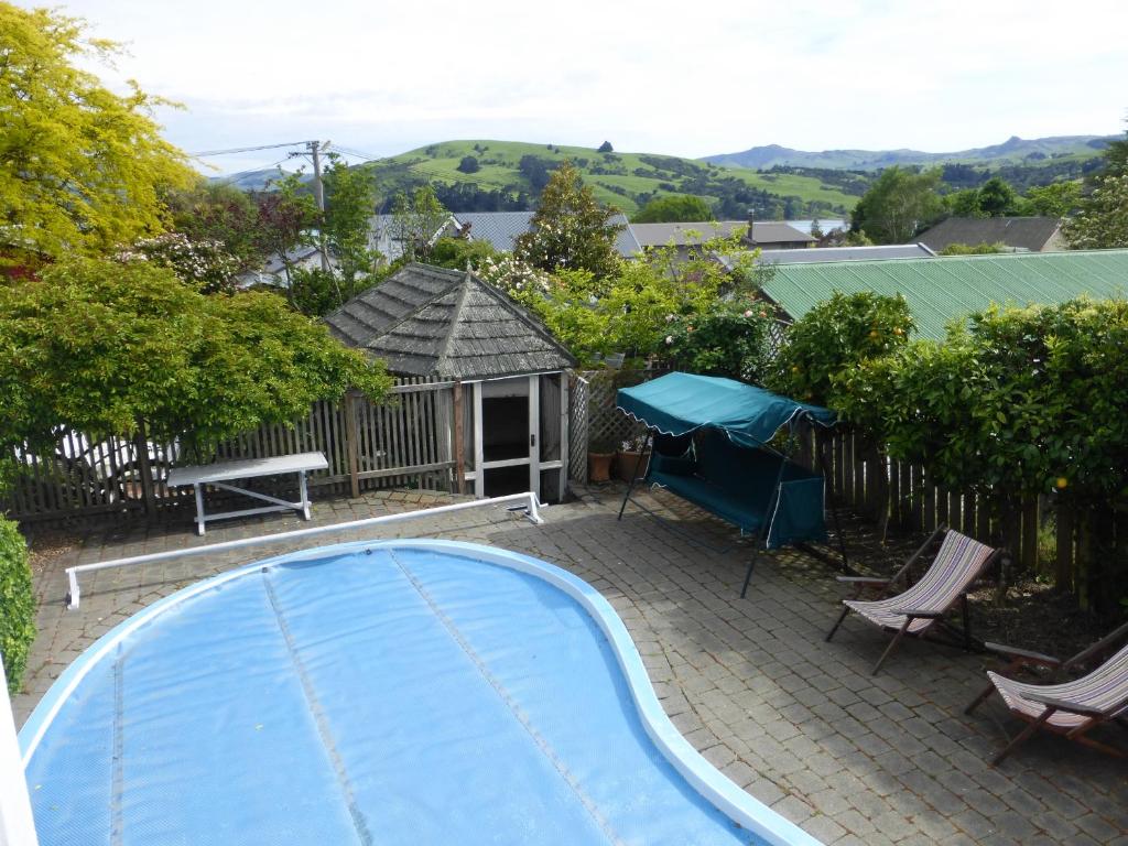 a swimming pool with chairs and a gazebo at The Summerhouse, Ideal Akaroa location. in Akaroa