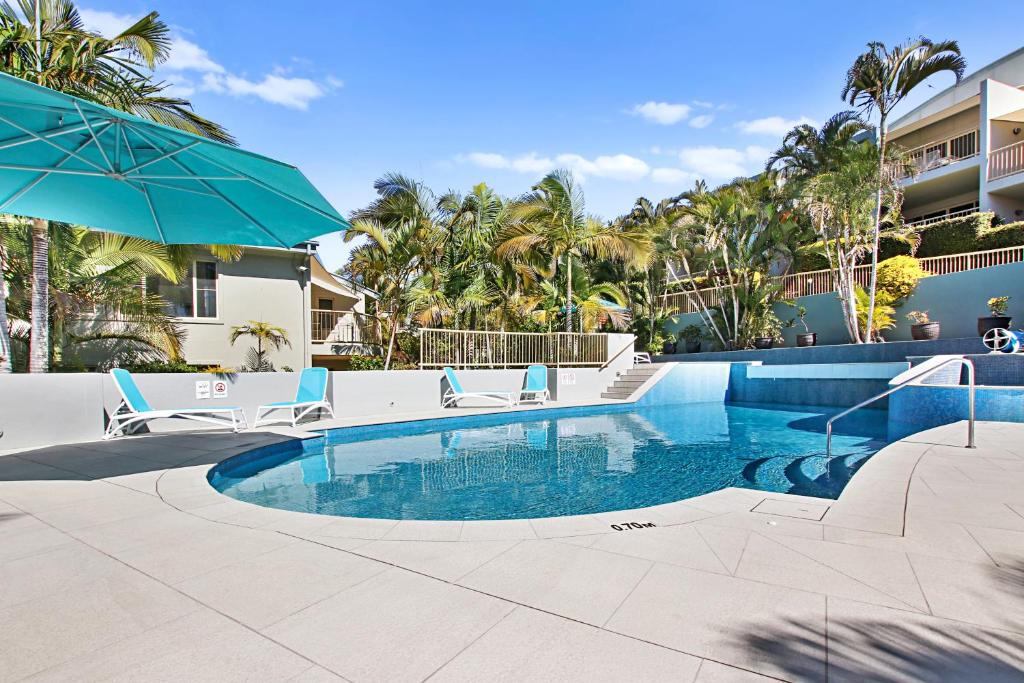 a swimming pool with chairs and an umbrella at Lennox Beach Resort in Lennox Head
