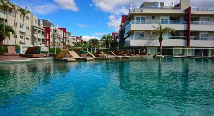 una piscina con tumbonas frente a un edificio en Lindo apto Campeche com vista mar e ótima area de lazer perto da praia, en Florianópolis