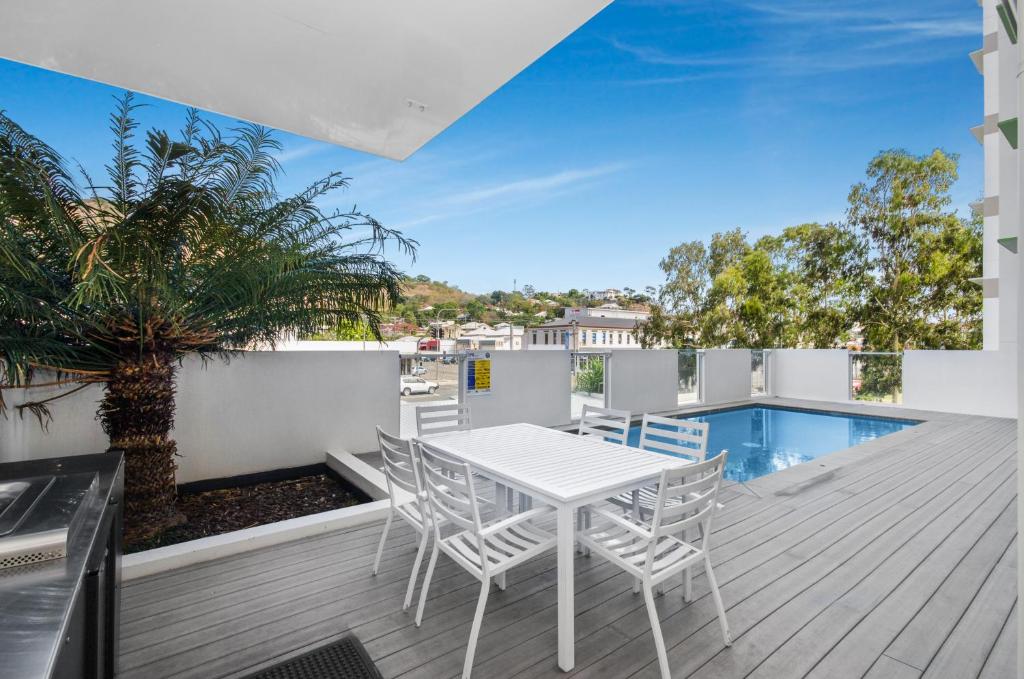 einen weißen Tisch und Stühle auf einer Terrasse mit einem Pool in der Unterkunft Central Kensington Apartments in Townsville