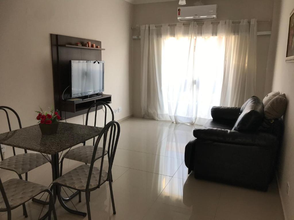 un soggiorno con tavolo, divano e TV di Mar azul Enseada a Guarujá