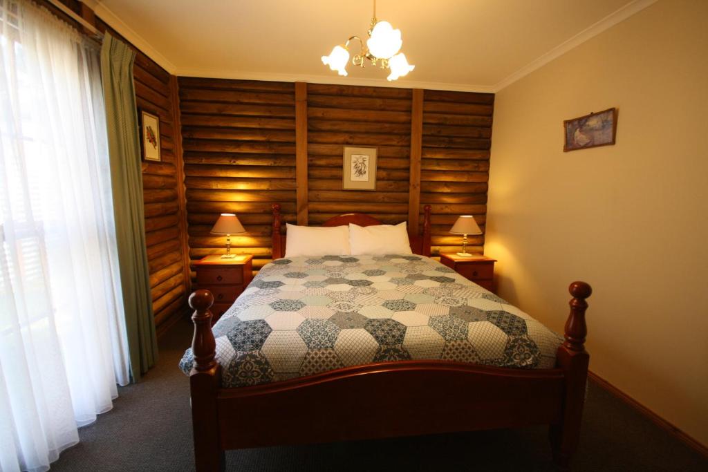 a bedroom with a bed and two lamps and a window at Halls Gap Log Cabins in Halls Gap