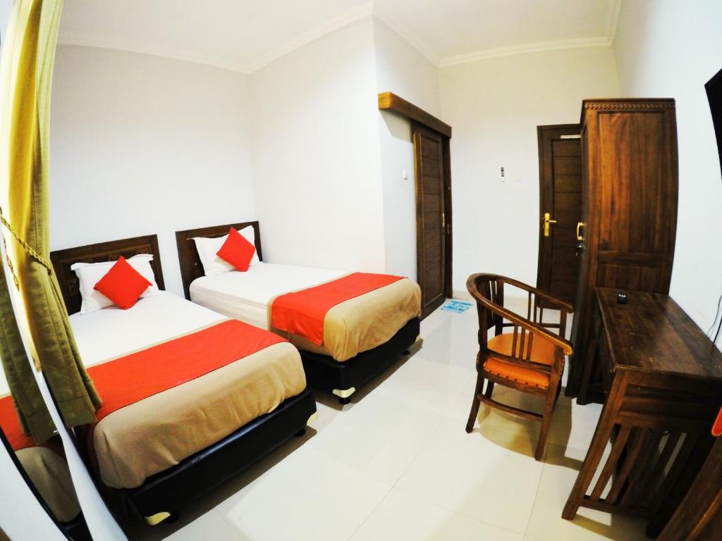 a hotel room with two beds and a desk at Griya Alsis Residence in Yogyakarta