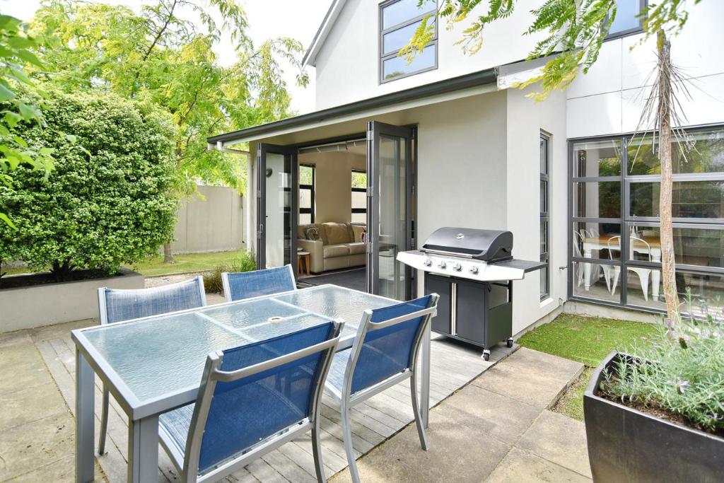un patio avec une table, des chaises et un grill dans l'établissement Hagley Apartment - Christchurch Holiday Homes, à Christchurch