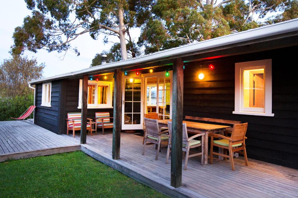 a house with a wooden deck with a table and chairs at The Apple Pickers' Cottages at Matahua in Mapua