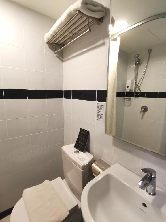 a bathroom with a sink and a toilet and a mirror at Kimberley Hotel Georgetown in George Town