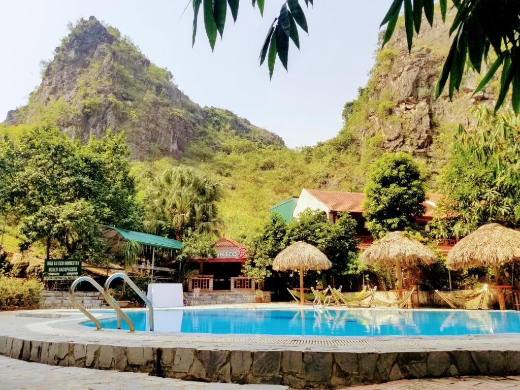 una piscina resort con una montaña en el fondo en Hoalu Ecolodge Homestay en Ninh Binh
