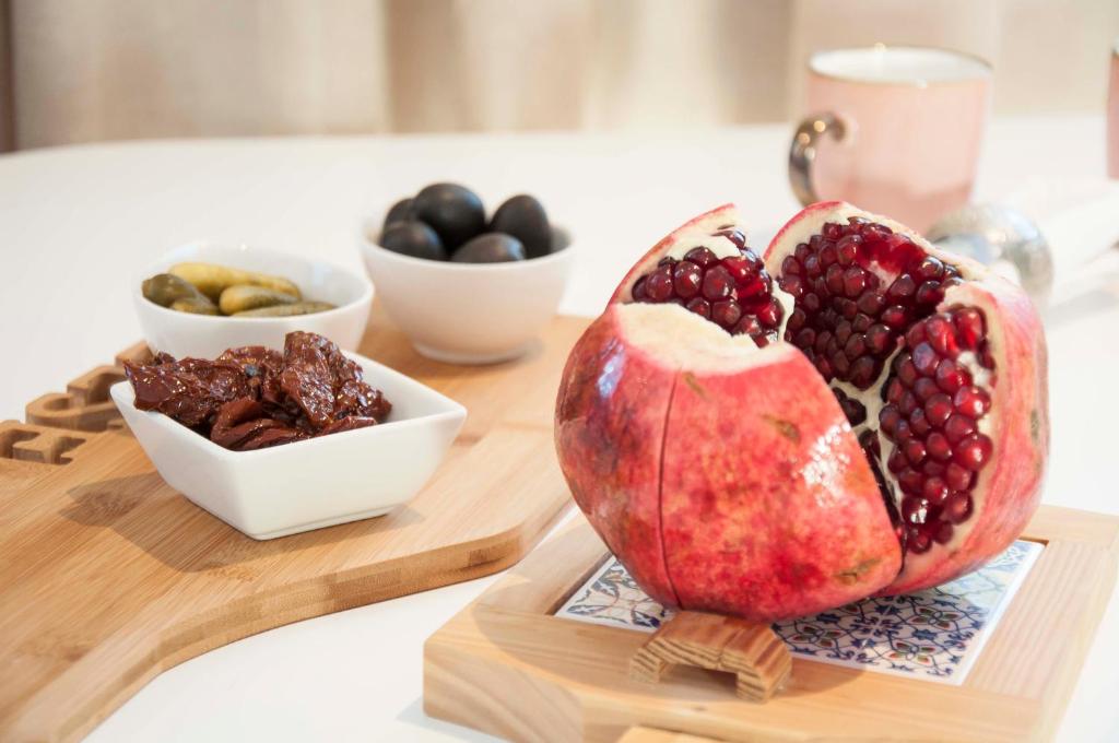 a pomegranate on a cutting board with bowls of fruit at Charme apartment in Jelgava
