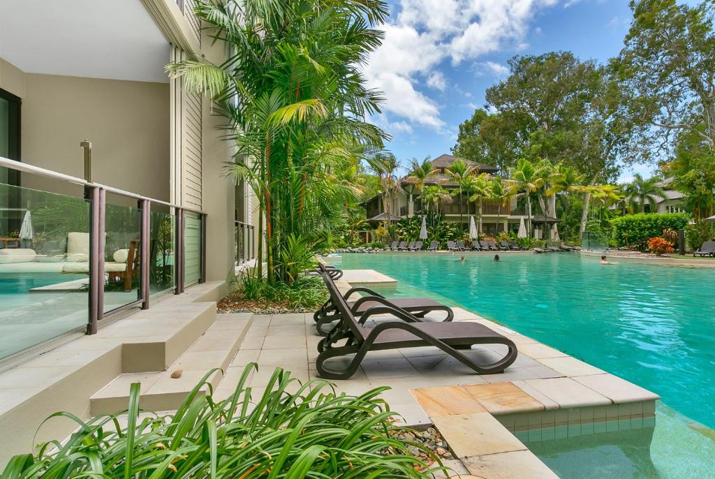 a swimming pool with two benches in front of a house at Swim Out Apartments in Triton Street Beachfront Resort Palm Cove in Palm Cove