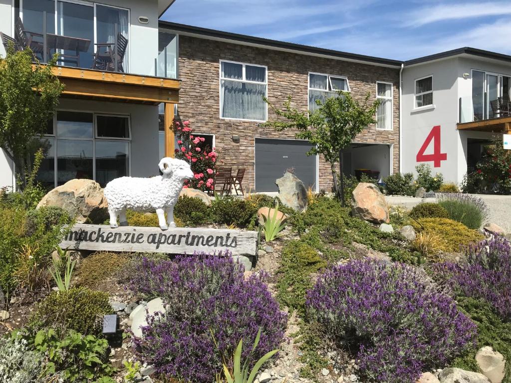 uma estátua de uma ovelha num cartaz num jardim em The Mackenzie Apartments em Lake Tekapo