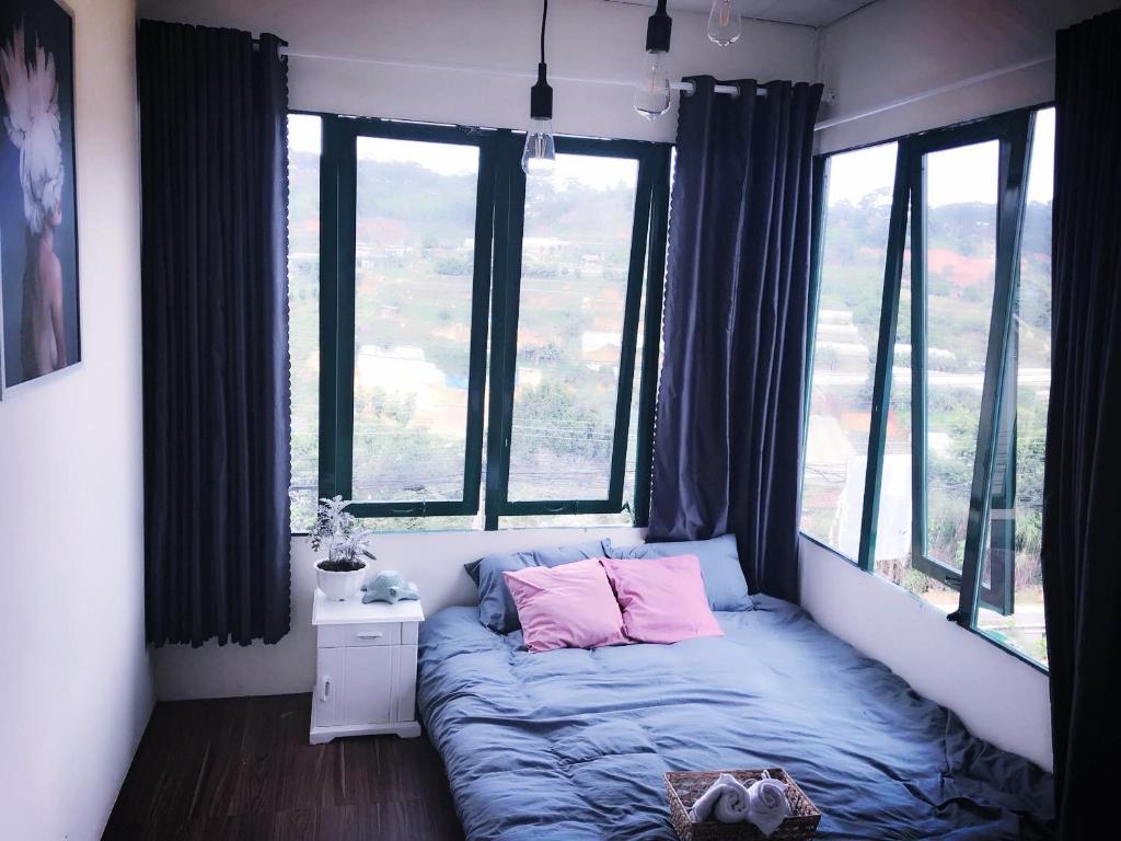 a bed in a room with large windows at Crush Va Toi in Da Lat