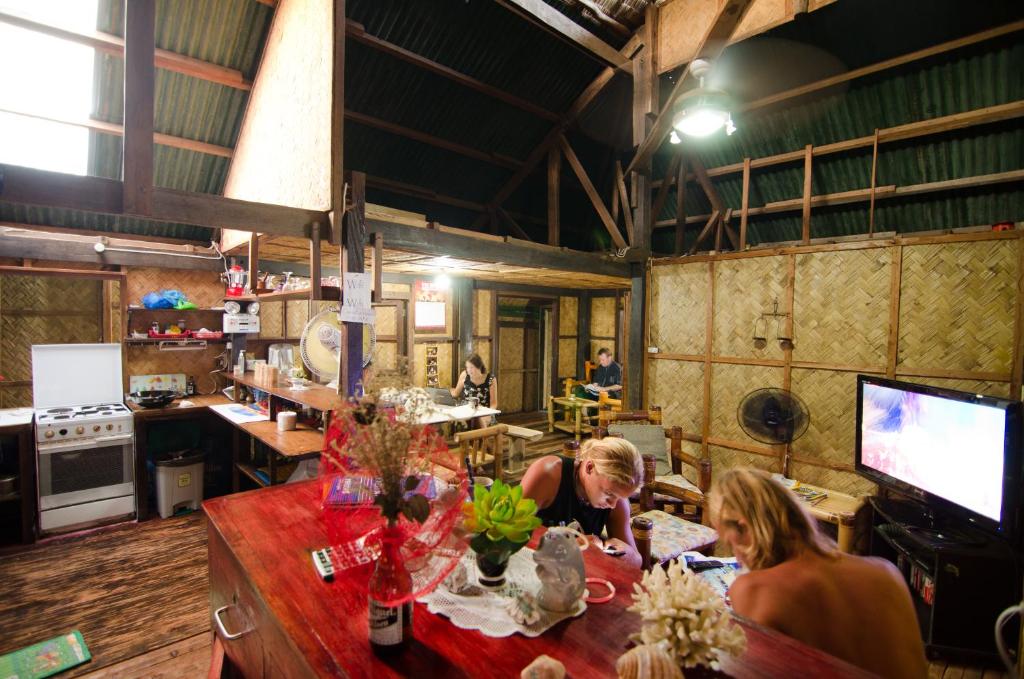 Dos mujeres sentadas en una mesa en una cocina en Coron Backpacker Guesthouse en Corón