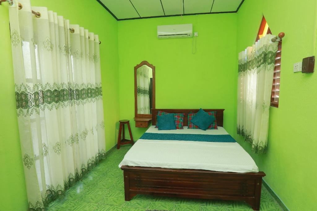 a bedroom with a bed with green walls and a mirror at Galle Paradise Inn in Galle