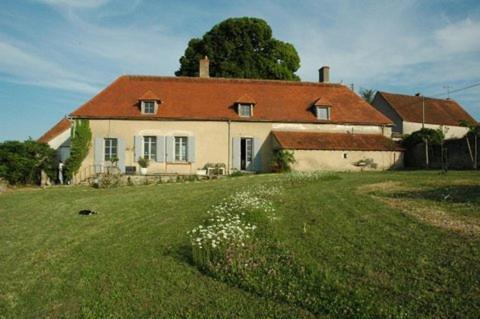 a white house with a red roof on a green field at Le Manoir de Presle - Chambres d'Hôte in Montaigu-le-Blin